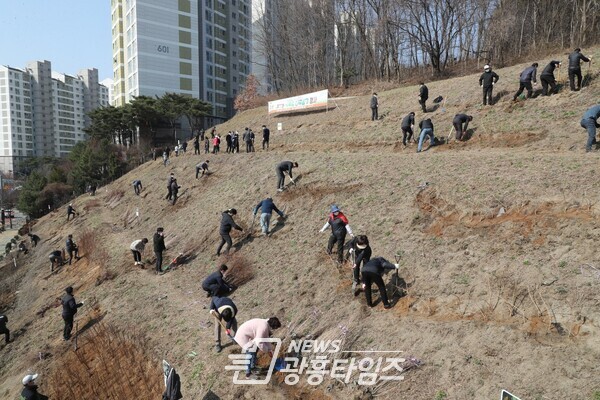  군포시 공직자와 주민 등 참석자들이, 부곡동 삼성마을 6단지 녹화터널 인근 경사지에서 식목일 기념 나무심기를 하고 있다(사진제공=군포시)